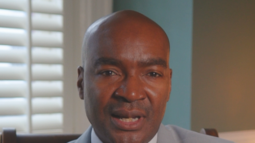 A Black man in a gray suit looks directly at the camera. Text overlay reads: "CONFRONTED BY THE FBI? YOUR RIGHTS."